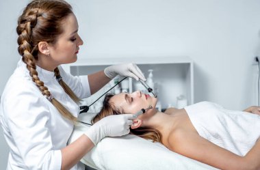 Genç bir kadın güzellik salonunda yüz masajı yaptırıyor.