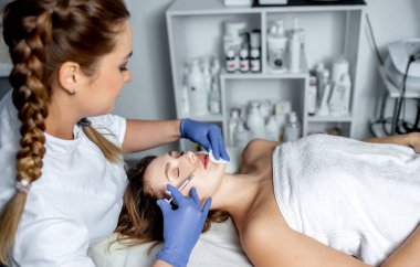 Genç bir kadın güzellik salonunda yüz masajı yaptırıyor.