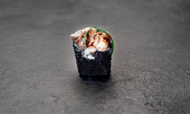 Suşi siyah tahta yüzeyde yuvarlanıyor.