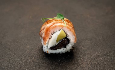 Suşi siyah tahta yüzeyde yuvarlanıyor.