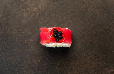 Suşi siyah tahta yüzeyde yuvarlanıyor.