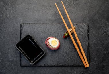 Çubuklu suşi nigiri ve siyah tahta üzerine soya sosu.