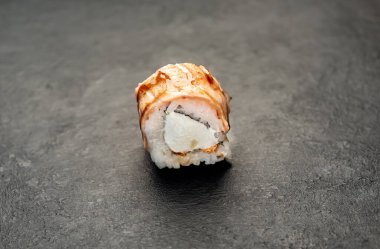 Suşi siyah tahta yüzeyde yuvarlanıyor.