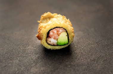 Suşi siyah tahta yüzeyde yuvarlanıyor.