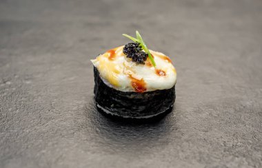 Suşi siyah tahta yüzeyde yuvarlanıyor.