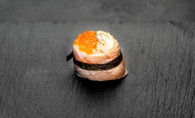 Suşi siyah tahta yüzeyde yuvarlanıyor.