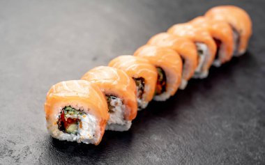 Suşi siyah tahta yüzeyde yuvarlanıyor.