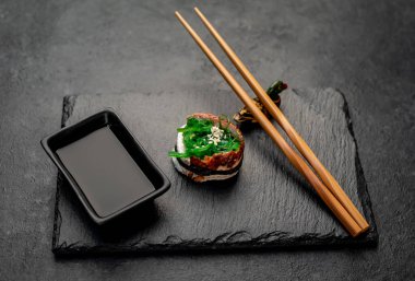 Çubuklu suşi nigiri ve siyah tahta üzerine soya sosu.