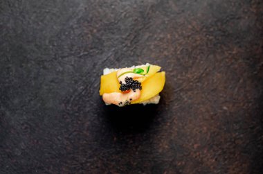 Suşi siyah tahta yüzeyde yuvarlanıyor.