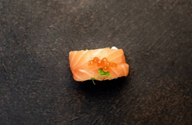 Suşi siyah tahta yüzeyde yuvarlanıyor.