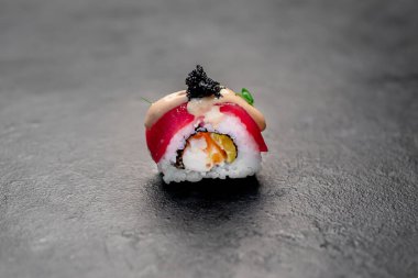 Suşi siyah tahta yüzeyde yuvarlanıyor.