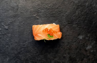 Suşi siyah tahta yüzeyde yuvarlanıyor.