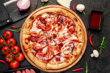 Siyah masa yüzeyinde malzemeleri olan pizza.