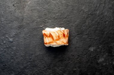 Suşi siyah tahta yüzeyde yuvarlanıyor.