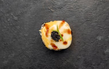 Suşi siyah tahta yüzeyde yuvarlanıyor.