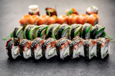 Sushi siyah taş arka planda yuvarlanıyor.