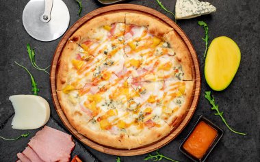 Siyah masa yüzeyinde malzemeleri olan pizza.