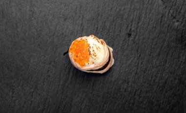 Suşi siyah tahta yüzeyde yuvarlanıyor.