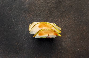 Suşi siyah tahta yüzeyde yuvarlanıyor.