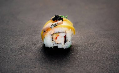 Suşi siyah tahta yüzeyde yuvarlanıyor.