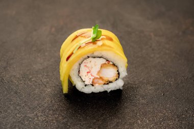 Suşi siyah tahta yüzeyde yuvarlanıyor.