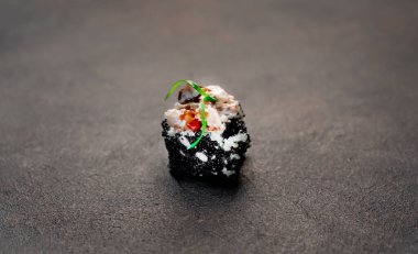 Suşi siyah tahta yüzeyde yuvarlanıyor.