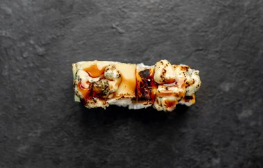 Suşi siyah tahta yüzeyde yuvarlanıyor.