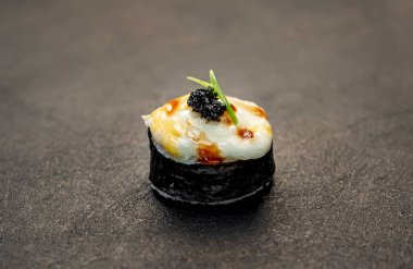 Suşi siyah tahta yüzeyde yuvarlanıyor.