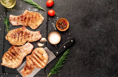 Baharatlı ızgara et ve siyah arka planda otlar.