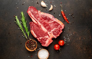 Biberiyeli çiğ biftek ve siyah masada domates.