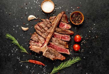 Baharatlı ızgara biftek ve siyah arka planda otlar.