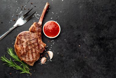 Baharatlı ızgara biftek ve siyah arka planda biberiye.