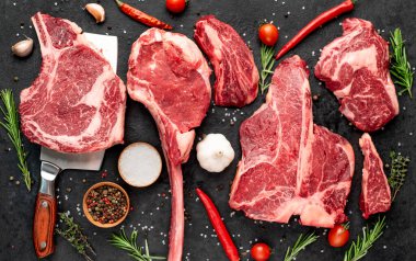 Siyah arka planda baharatlı ve sebzeli çiğ biftek.