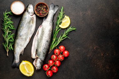 Baharatlı çiğ dorado balığı ve siyah arka planda otlar.