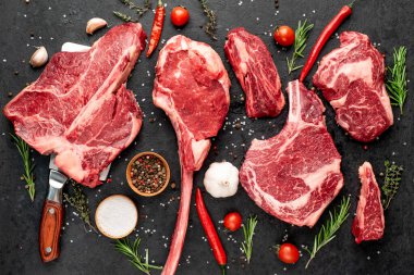 Siyah arka planda baharatlı ve sebzeli çiğ biftek.