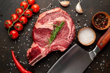 Baharatlı çiğ biftek ve siyah arka planda otlar.