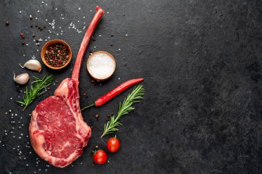 Siyah arka planda baharatlı ve sebzeli çiğ biftek.