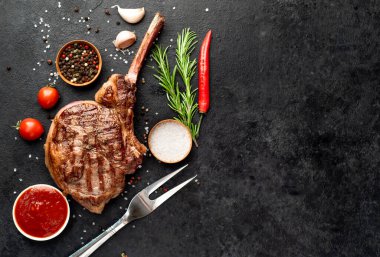Biberiyeli ızgara biftek ve siyah arka planda baharatlar.