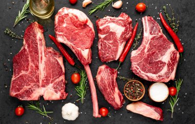 Siyah arka planda baharatlı ve sebzeli çiğ biftek.