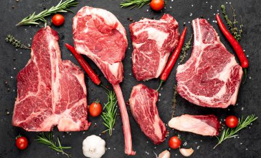 Siyah arka planda baharatlı ve sebzeli çiğ biftek.