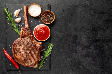 Baharatlı ızgara biftek ve siyah arka planda biberiye. en üstteki görünüm.