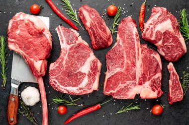 Siyah arka planda baharatlı ve sebzeli çiğ biftek.