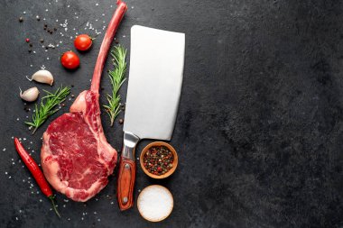 Siyah arka planda baharatlı ve sebzeli çiğ biftek.