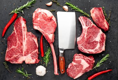 Siyah arka planda baharatlı ve sebzeli çiğ biftek.