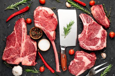 Siyah arka planda baharatlı ve sebzeli çiğ biftek.