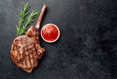 Biberiyeli ızgara biftek ve siyah arka planda baharatlar.