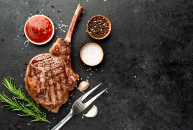 Baharatlı ızgara biftek ve siyah arka planda sebze.