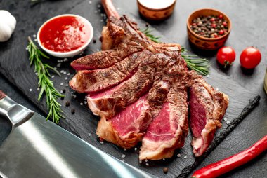 Siyah arka planda baharatlı ızgara biftek ve otlar.