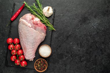 Baharatlı çiğ hindi budu ve siyah arka planda otlar. Üst Manzara. Metnin için boş yer.