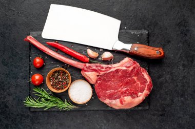 Siyah arka planda baharatlı ve sebzeli çiğ biftek.